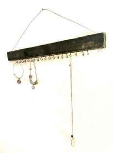 a wall mounted jewelry rack with two pairs of earrings hanging from it's hooks