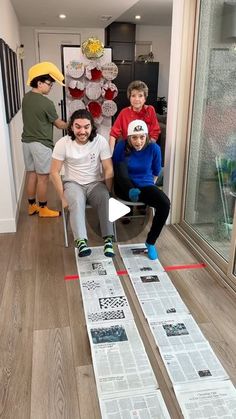 three men sitting on chairs in front of a window with newspaper taped to the floor