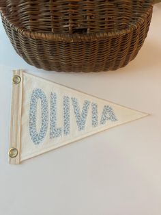 a woven basket next to a cloth banner with the word oliva printed on it