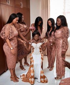 a group of women standing next to each other in front of a mirror wearing dresses