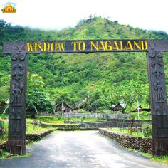 a sign that says window to nagaland on the side of a road in front of a lush green mountain