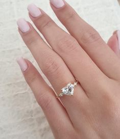 a woman's hand with a diamond ring on top of her finger and the other hand holding an engagement ring