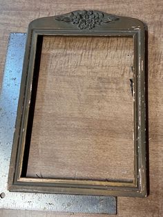 an old metal frame sitting on top of a wooden table next to a measuring ruler