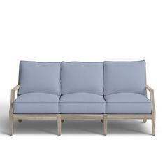 a light blue couch sitting on top of a white floor next to a wooden frame