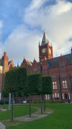 a large building with a clock on the top of it's tower and trees in front of it