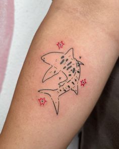 a small tattoo on the arm of a person with a shark and stars around it