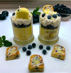 two desserts with blueberries, lemon and whipped cream in them on a table