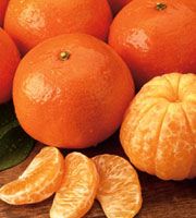 an orange cut in half sitting on top of a wooden table next to other fruit