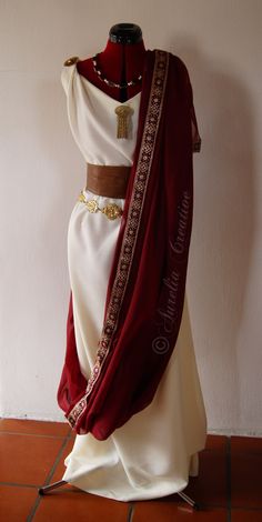 a mannequin dressed in a white dress with red and gold trimmings