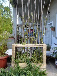 a wooden box with plants growing out of it in the middle of a patio area