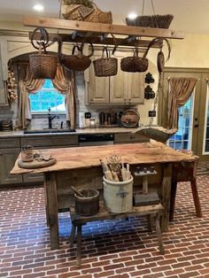 a kitchen with an island made out of wood and baskets hanging from it's ceiling