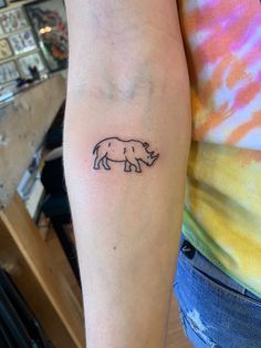 a small rhino tattoo on the arm