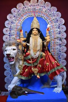 a statue of the hindu god sitting on top of a lion's head in front of a blue backdrop