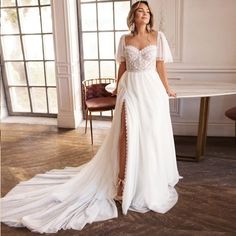 a woman in a white wedding dress standing next to a table with chairs and windows