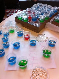 the table is covered with plastic cups filled with different colored liquids and monsters faces