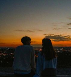 a man and woman are looking at the sunset