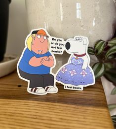 a couple of stickers sitting on top of a wooden table next to a potted plant