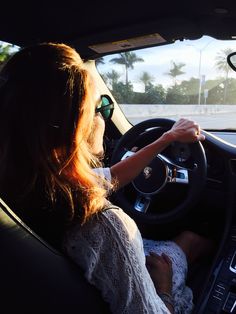 a woman driving a car with her baby in the passenger seat and sun shining through the windshield