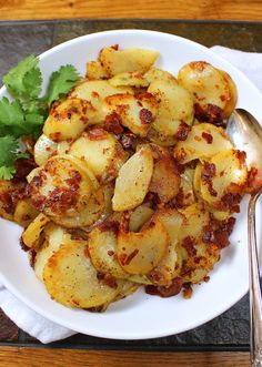 a white plate topped with potatoes covered in sauce and garnished with cilantro