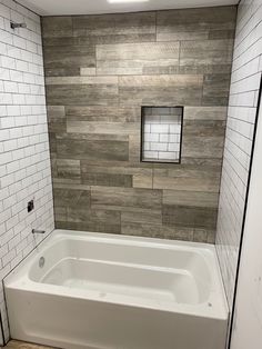 a white bath tub sitting inside of a bathroom next to a tiled wall and floor