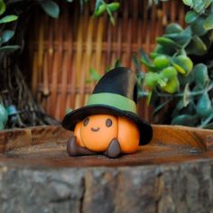 a small pumpkin with a hat on it's head sitting in front of a tree stump