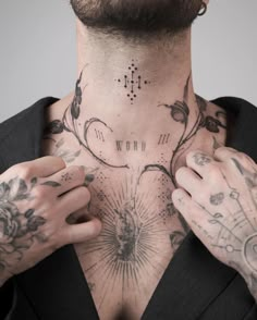 a man with lots of tattoos on his chest is holding his hands to his chest