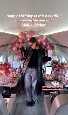 a woman is standing in the back of an airplane with balloons and cake on it