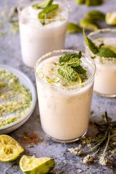 two glasses filled with ice cream and mint garnish next to sliced limes