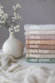 a stack of towels sitting on top of a table next to a vase with flowers