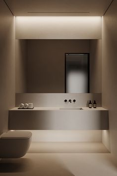 a white toilet sitting next to a bathroom sink under a mirror in a room with lights on