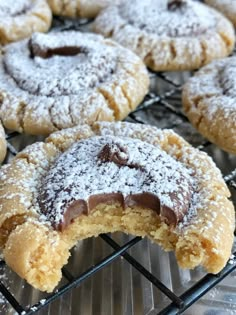 some cookies are cooling on a rack with powdered sugar and chocolate in the middle