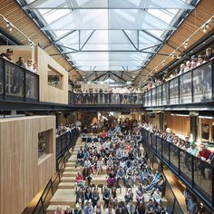 a large group of people standing inside of a building with lots of glass on the ceiling