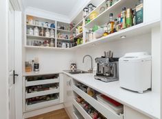 a kitchen with white cabinets and shelves filled with food