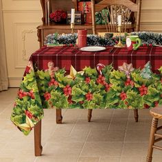 a christmas table cloth with holly and poinsettis on it, next to a wooden chair