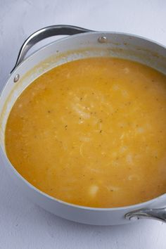 a white bowl filled with soup sitting on top of a table next to a spoon