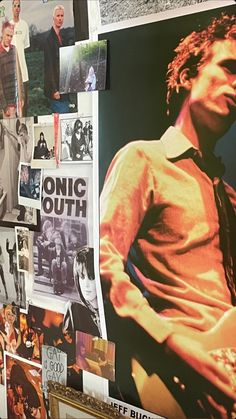 a wall covered in posters and pictures of men with guitars, guitars and other musical instruments