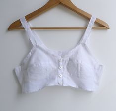 "Brand new vintage deadstock from the 1970's. Soviet era white longline bra top in 100% cotton. Features darted bra cups with circle stitching to the bottom half, slim shoulder straps & a sweet picot trim to the bustline. Closes with a column of buttons to the center front. Could be worn as an undergarment, or even as a cropped camisole top. 100% cotton takes dye well & could be a fun project too! Check out other brassieres in the shop - www.etsy.com/shop/fivestonesvintage?section_id=100 Vintage Bra, Cotton Bra, Bra Items, Cropped Camisole, Cotton Bras, Cute Bras, Longline Bra, Bra Top, Bra Cups