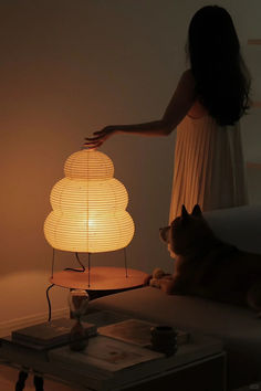 a woman standing next to a lamp with a dog laying on the floor in front of it