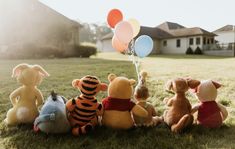 winnie the pooh and friends are sitting on the grass with balloons in front of them