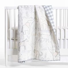 a white crib with a blue checkered blanket on it and an elephant design