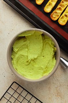 a bowl filled with green guacamole next to bread sticks