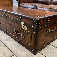 an old trunk is sitting on the floor in front of a leather couch and loveseat