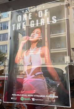 a poster is hanging in the window of a building with an advertisement on it that says, one of the girls available on all music streaming platforms