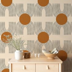 a wooden table topped with a vase filled with flowers next to a wallpaper covered in circles