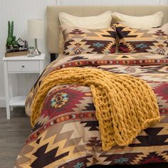 a bed with a brown and yellow blanket on top of it next to a night stand