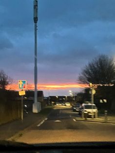 the sun is setting over an intersection with cars driving down it and street lights on either side