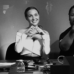 black and white photograph of two women sitting at a table with their hands folded in front of them