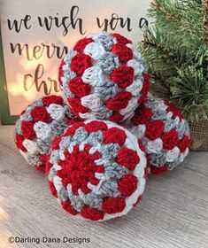 three red and white crocheted balls sitting on top of a table next to a christmas tree