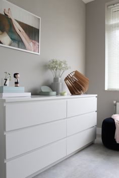 a white dresser sitting in a bedroom next to a window