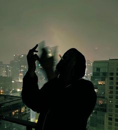 a person standing on top of a tall building looking at the city lights in the distance